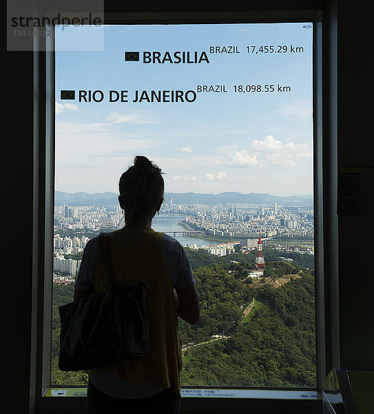 Eine Frau steht am Fenster des Seoul Tower mit Blick auf die Stadt Seoul; Seoul  Südkorea