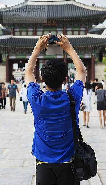 Tourist hält eine Kamera für ein Foto im Gyeongbokgung-Palast hoch; Seoul  Korea'.