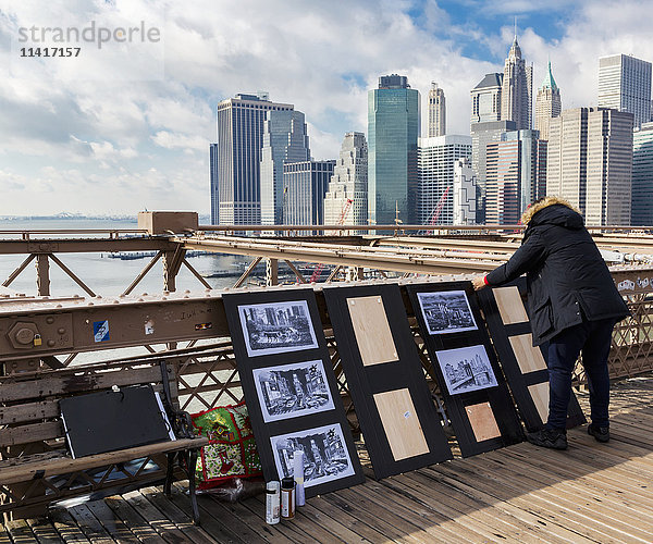 Blick auf die Skyline von New York City von der Brooklyn Bridge aus mit einem Kunsthändler im Vordergrund; New York City  New York  Vereinigte Staaten von Amerika'.
