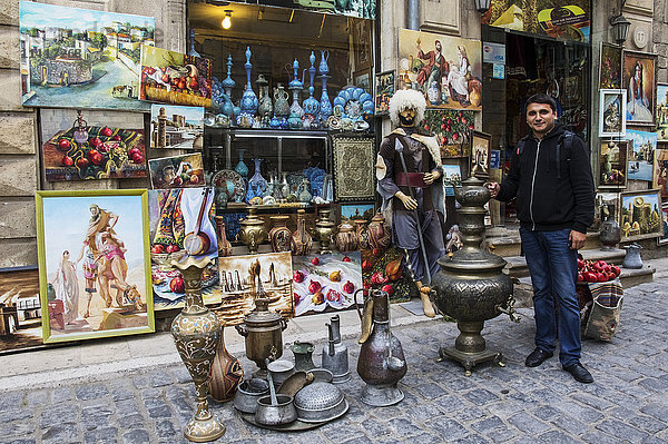 Mann steht neben Verkaufsgegenständen in einem Souvenirladen; Baku  Aserbaidschan'.