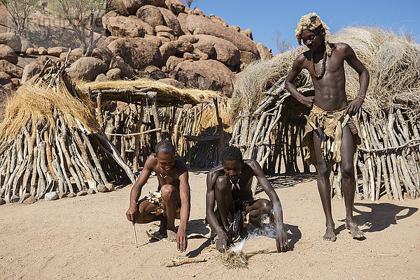 Damara-Volk in traditioneller Kleidung versucht  das Lebende Museum der Damara in Brand zu setzen; Namibia'.