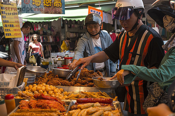 Szene aus der Gemeinde Luodong im Landkreis Yilan: Einige Einheimische sind gerade von ihren Motorrollern abgestiegen und kaufen auf dem Markt Snacks; Taiwan  China'.