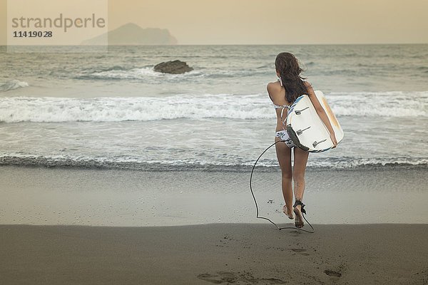Eine Surferin trägt ihr Longboard ins Meer  Strand von Waiao im Bezirk Yilan; Taiwan  China'.