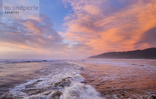 Kräftig roter Sonnenuntergang über Cobden Beach und Wellen  Sonnenuntergang spiegelt sich im Meer; Greymouth  Südinsel  Neuseeland'.