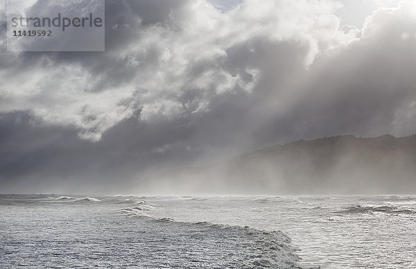 Strahlen brechen durch stürmische Wolken über brechenden Wellen; Greymouth  Südinsel  Neuseeland'.