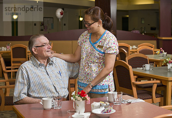 Seniorin und Betreuerin in der Cafeteria; Devon  Alberta  Kanada'.
