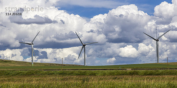 Windkraftanlagen auf einem Feld mit Bahngleisen  mit Wolken; Pincher Creek  Alberta  Kanada'.