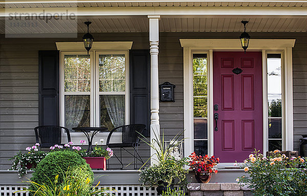 Vordere Veranda eines Hauses mit dekorativen Pflanzen und Blumen und einer roten Tür; Knowlton  Quebec  Kanada'.