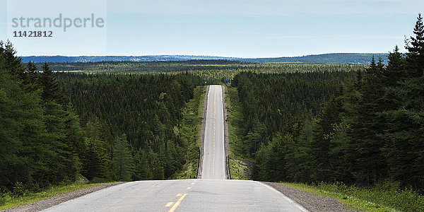 Eine Straße führt in ein Tal hinunter und wieder hinauf und führt in die Ferne; Pleasant Bay  Nova Scotia  Kanada'.