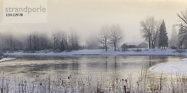 Sanfter goldener Himmel und ein ruhiger See bei Sonnenaufgang im Winter; Prince George  British Columbia  Kanada'.