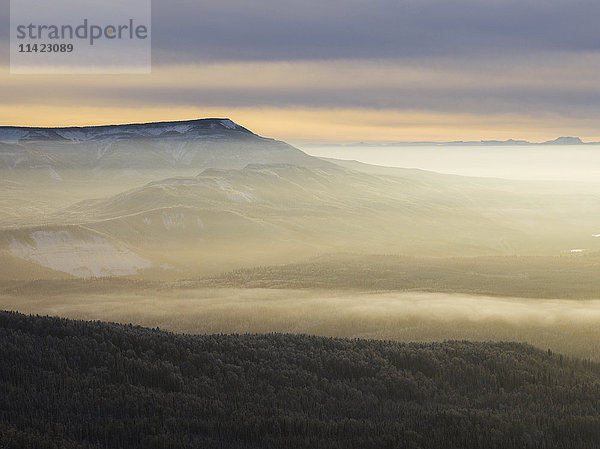 Nebel über der schneebedeckten Landschaft der zerklüfteten kanadischen Rocky Mountains und einem Wald im Winter; British Columbia  Kanada'.