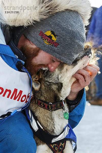 Wade Marrs umarmt einen seiner Leithunde nach seinem 4. Platz im Ziel in Nome beim Iditarod 2016  Alaska