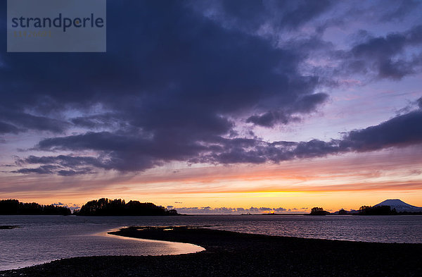 Dramatischer Himmel bei Sonnenuntergang über dem Ozean und der silhouettierten Küstenlinie; Sitka  Alaska  Vereinigte Staaten von Amerika