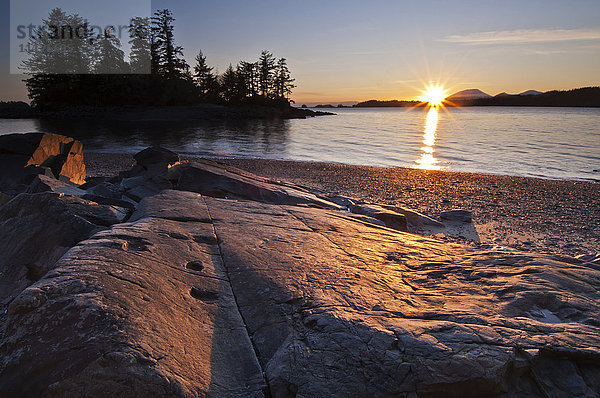 Blick auf Magic Island und den Sonnenuntergang hinter Mt. Edgecombe von den Felsen und dem Strand der Halibut Point Recreation Area; Sitka  Alaska  Vereinigte Staaten von Amerika'.