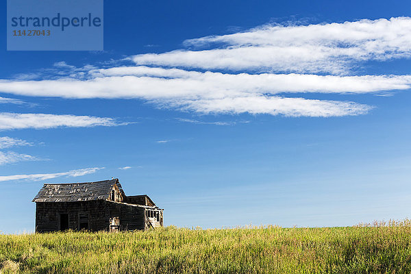 Alte Holzscheune in einem Feld mit Wolken und blauem Himmel  südlich von Strathmore; Alberta  Kanada'.