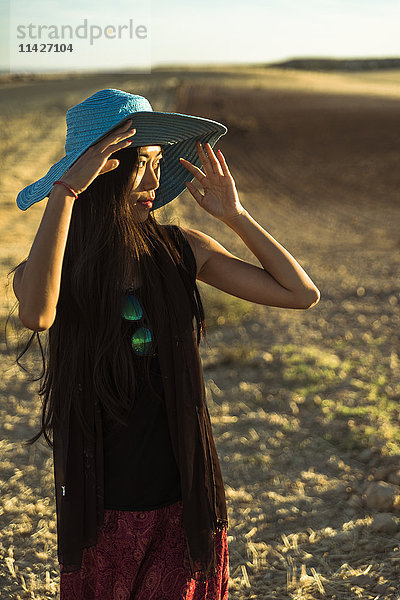 Eine junge asiatische Frau  die in einem goldenen Weizenfeld spazieren geht; Madrid  Spanien'.