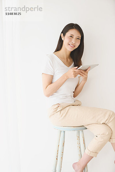 Junge japanische Frau auf einem Stuhl in einem weißen Raum