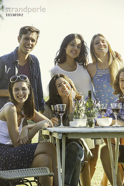Freunde posieren für ein Foto beim gemeinsamen Essen im Freien