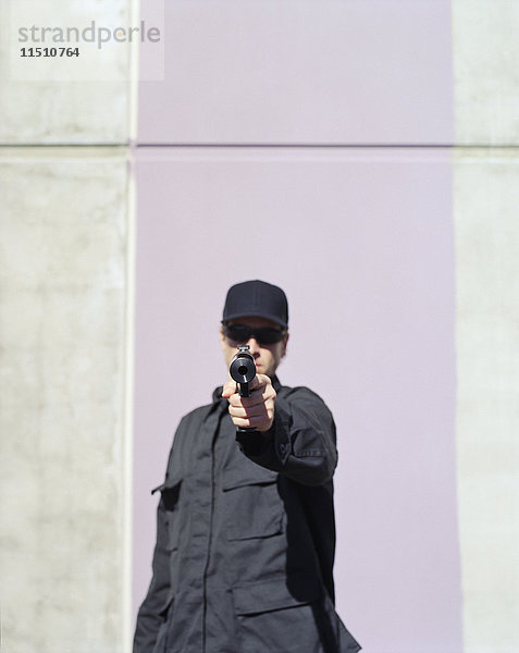 Mann in Spezialeinheiten  der mit einer Hochleistungs-Handfeuerwaffe mit angebrachtem Schalldämpfer zielt