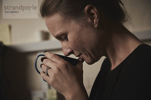 Eine Frau hält sich eine frisch gebrühte Tasse Kaffee an die Nase.
