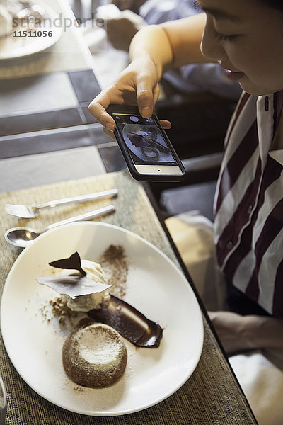 Frau fotografiert mit dem Smartphone Gourmet-Dessert im Restaurant