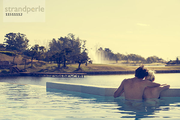 Paar Entspannung im Infinity-Pool mit Blick auf den See