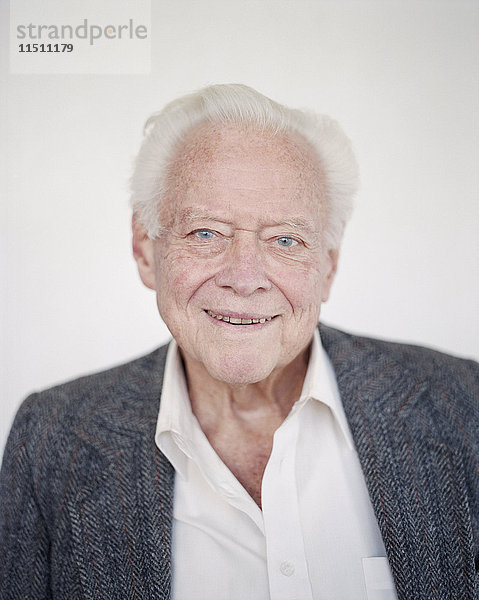 Porträt eines älteren Mannes mit grauem Haar in einem Hemd mit offenem Hals  lächelnd.