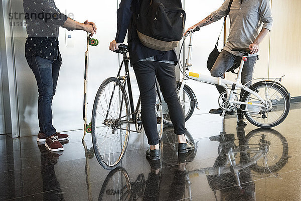 Männer warten auf Aufzug mit Fahrrädern und Longboard  niedrige Sektion
