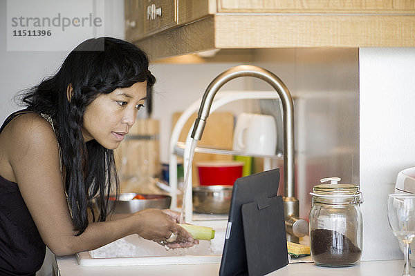 Frau benutzt digitale Tabletten bei der Zubereitung von Speisen zu Hause