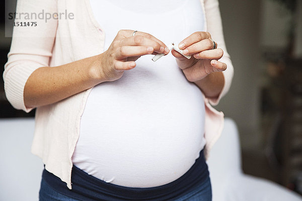 Schwangere Frau  die die Zigarette zerbricht