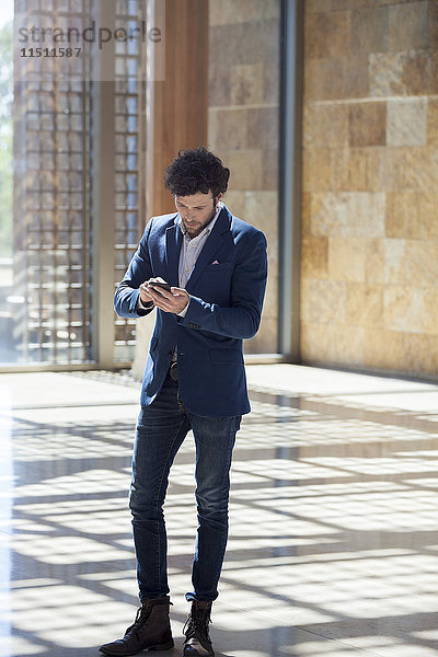 Man Text-Messaging während des Spaziergangs durch die Lobby
