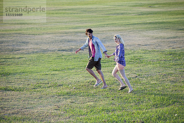 Paar läuft zusammen im Feld  hält sich an den Händen.