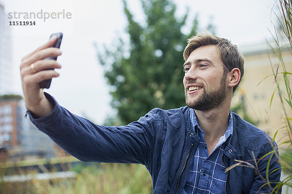 Junger Mann benutzt Smartphone  um einen Selfie nach draußen zu bringen.