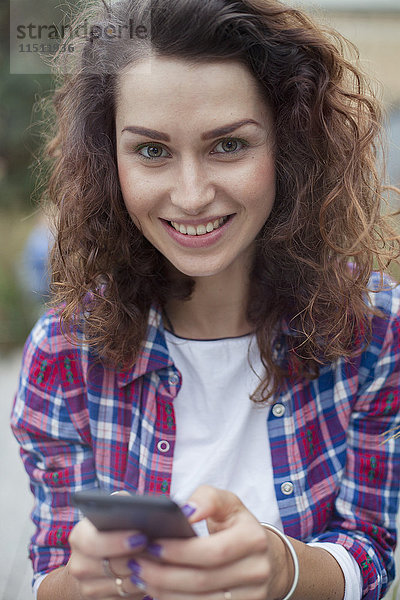 Junge Frau mit Smartphone  lächelnd  Portrait