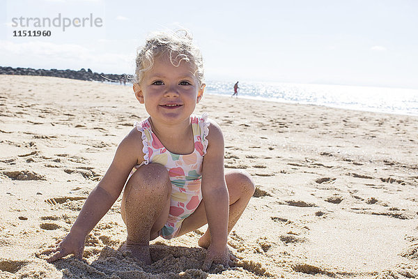 Kleines Mädchen spielt mit Sand am Strand