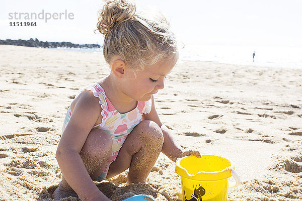 Kleines Mädchen spielt im Sand am Strand