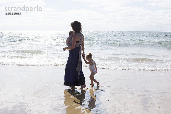 Mutter und Kinder beim Spaziergang am Strand