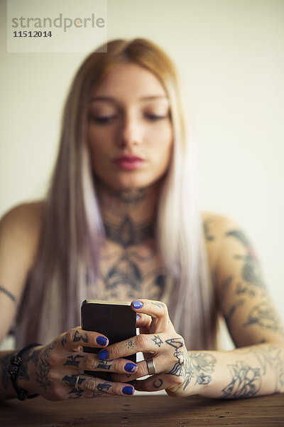 Tätowierte Frau mit Smartphone