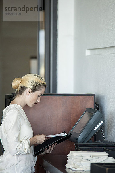 Kellnerin mit computergestützter Kasse im Restaurant