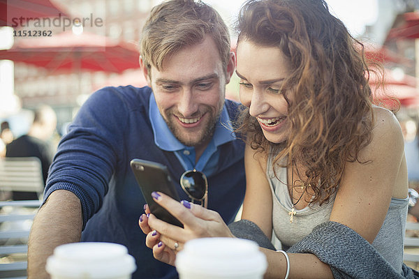 Paar  das sich das Smartphone gemeinsam im Freien anschaut