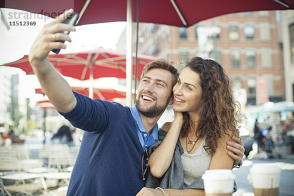 Pärchen posieren für einen Selfie im Outdoor-Café