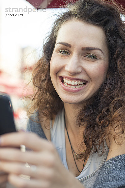 Junge Frau mit Smartphone  lächelnd  Portrait