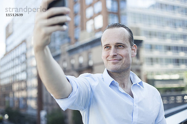 Mann  der ein Handy benutzt  um einen Selfie zu nehmen.