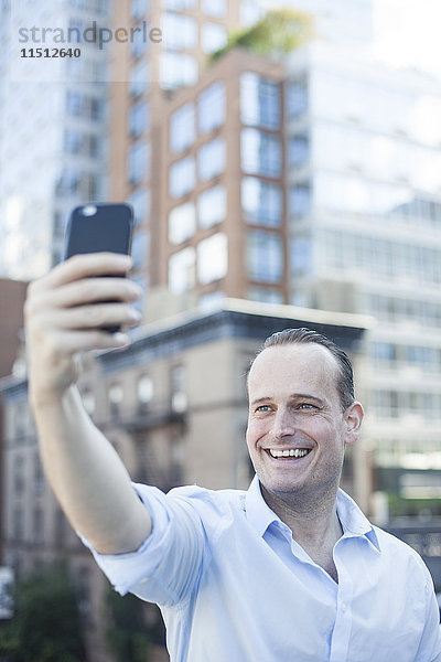 Mann  der ein Smartphone benutzt  um einen Selfie zu nehmen.