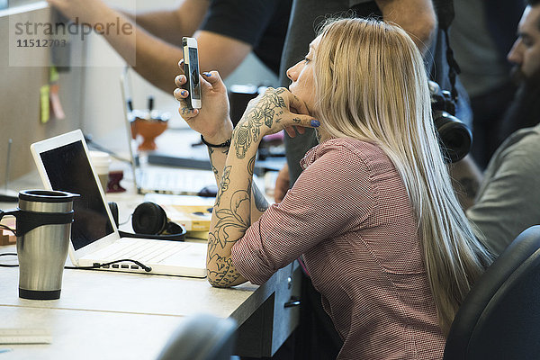 Junge Frau starrt auf Smartphone im Büro