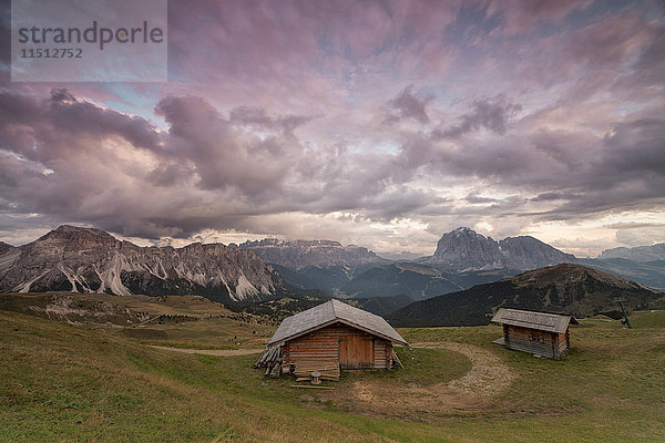 Rosa Wolken bei Sonnenuntergang auf den typischen Hütten der Geislergruppe von Seceda aus gesehen  Gröden  Trentino-Südtirol  Italien  Europa
