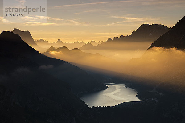 Oranger Lichtstrahl und Nebel auf den Gipfeln der Dolomiten und dem Fedaia-Pass  Cima Belvedere  Fassatal  Trentino-Südtirol  Italien  Europa