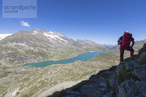 Wanderer bewundert den blauen Alpensee vom Pizzo Campaccio  Berninapass  Kanton Graubünden  Engadin  Schweizer Alpen  Schweiz  Europa