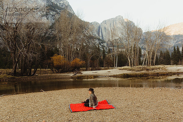 Frau sitzt auf einer roten Decke und schaut auf die Landschaft  Yosemite National Park  Kalifornien  USA