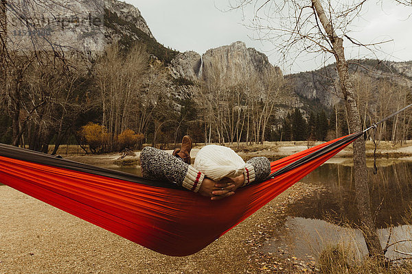 Rückansicht einer in roter Hängematte liegenden Frau mit Blick auf die Landschaft  Yosemite National Park  Kalifornien  USA